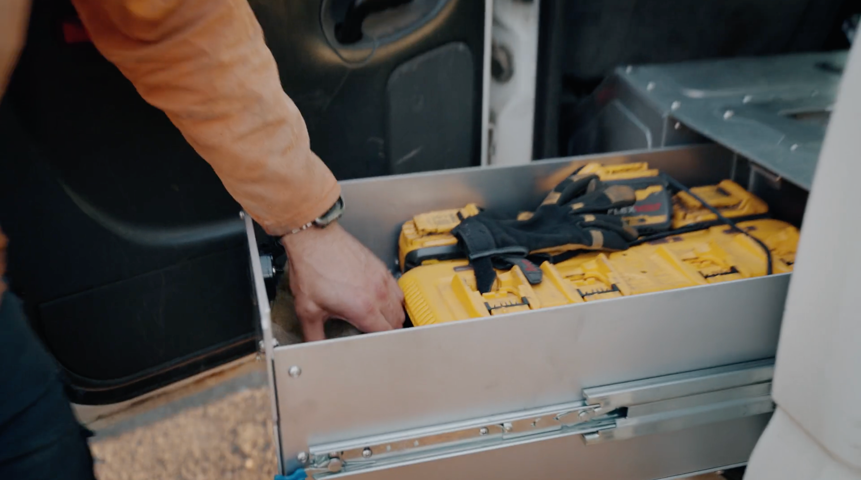 Rig welder accessing storage drawer in The Highway Tight aluminum seat delete system with tool cases inside.
