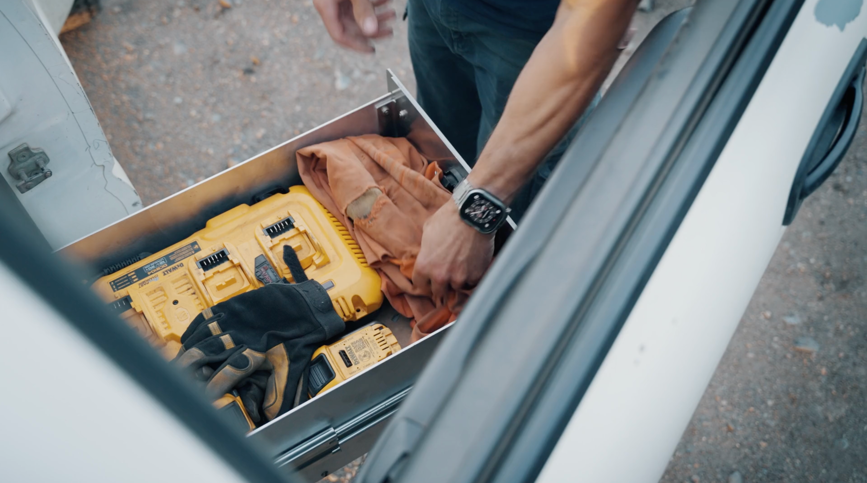 Rig welder reaching into The Highway Tight aluminum seat delete drawer system with tools and work gear inside.